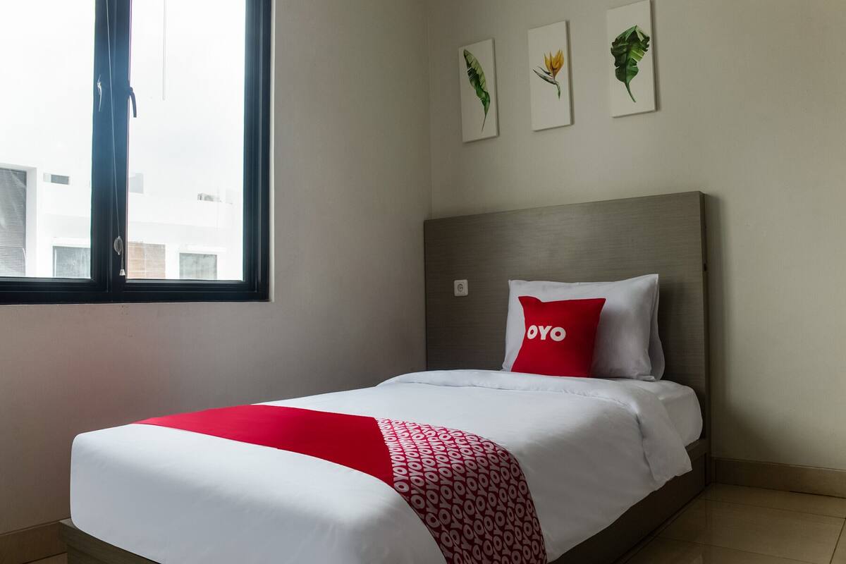 A hotel room with a bed, a window, and wall art.