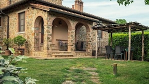 A stone building with a covered patio area, outdoor seating, and a well-maintained lawn. - Rustico Relax Explore Tuscany (Santa Maria)