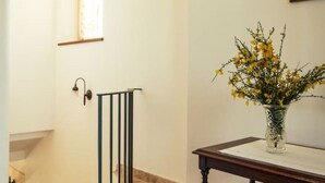 A hallway with a wooden table, a vase of yellow flowers, and a black railing. - Rustico Relax Explore Tuscany (Santa Maria)