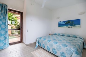 A bedroom with a bed, a painting, a window, and a door.