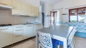 Una cocina moderna con armarios blancos, una isla central y un comedor con sillas blancas.