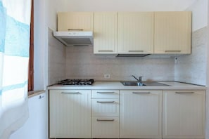 A kitchen with light-colored cabinets, a gas stove, and a sink.