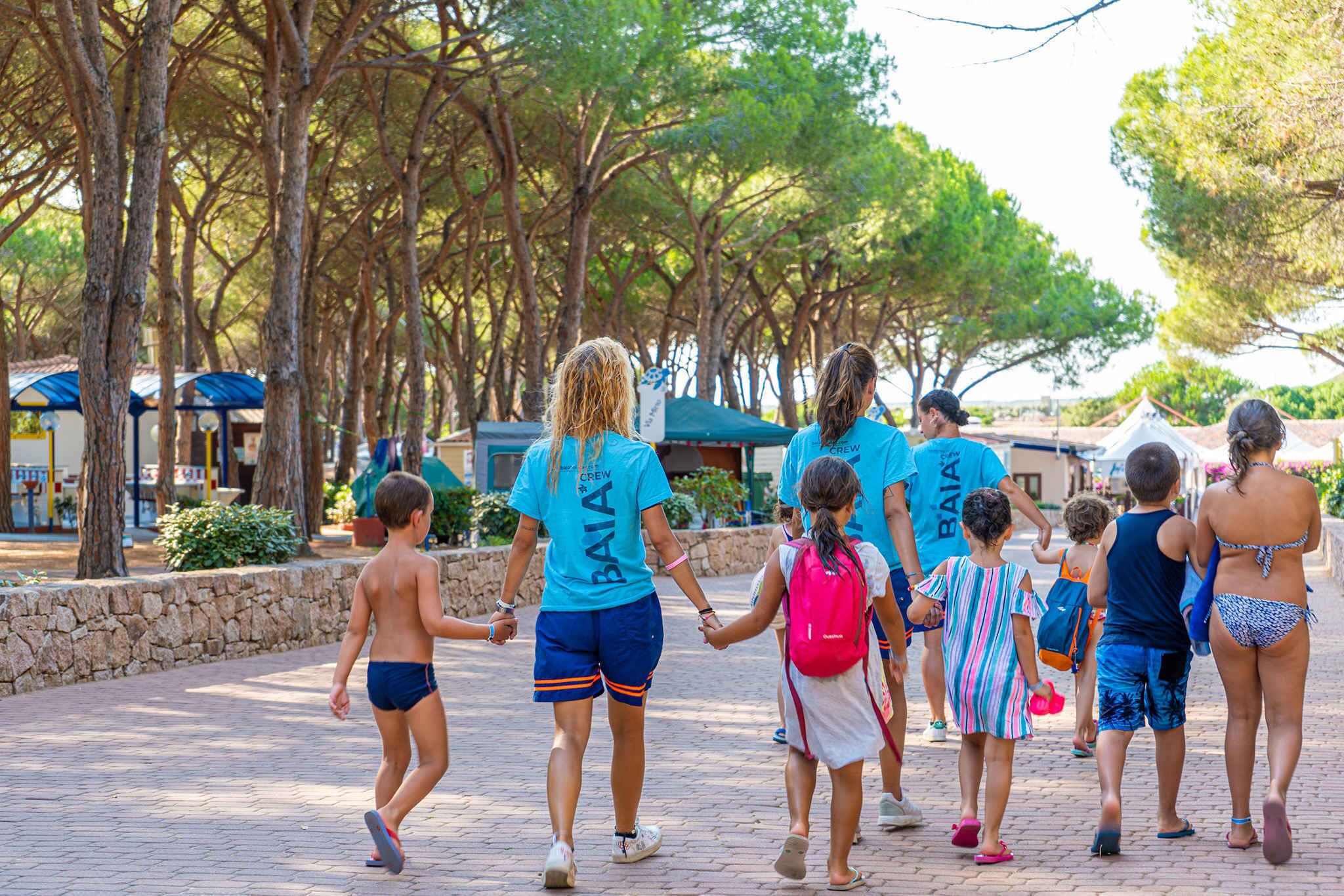 A group of people walking on a paved path surrounded by trees.
