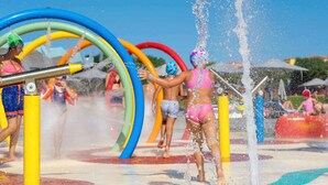 Een waterpark met kleurrijke glijbanen en een fontein in het midden.