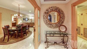 Un coin repas avec une table ronde et des chaises, un lustre et un miroir décoratif au mur.