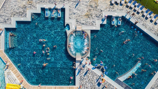 Una grande piscina all'aperto con diverse corsie e una zona idromassaggio centrale.