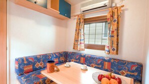 Un angolo cottura accogliente con un tavolo di legno, una panca azzurra decorata e una finestra con tende a motivi.