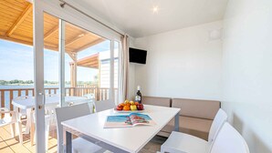 Una habitación moderna con una mesa blanca, sillas, un sofá y un televisor en la pared.