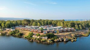 A campground with multiple RV-style cabins arranged in rows, surrounded by trees and a body of water. - Mobile home with pool for 6 people (Fertilia)