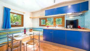 Una cocina moderna con armarios azules, una mesa de comedor de madera y una ventana con vistas a zonas verdes.