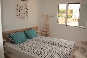 Un dormitori amb un llit, una escala de fusta, una finestra i una decoració mural.