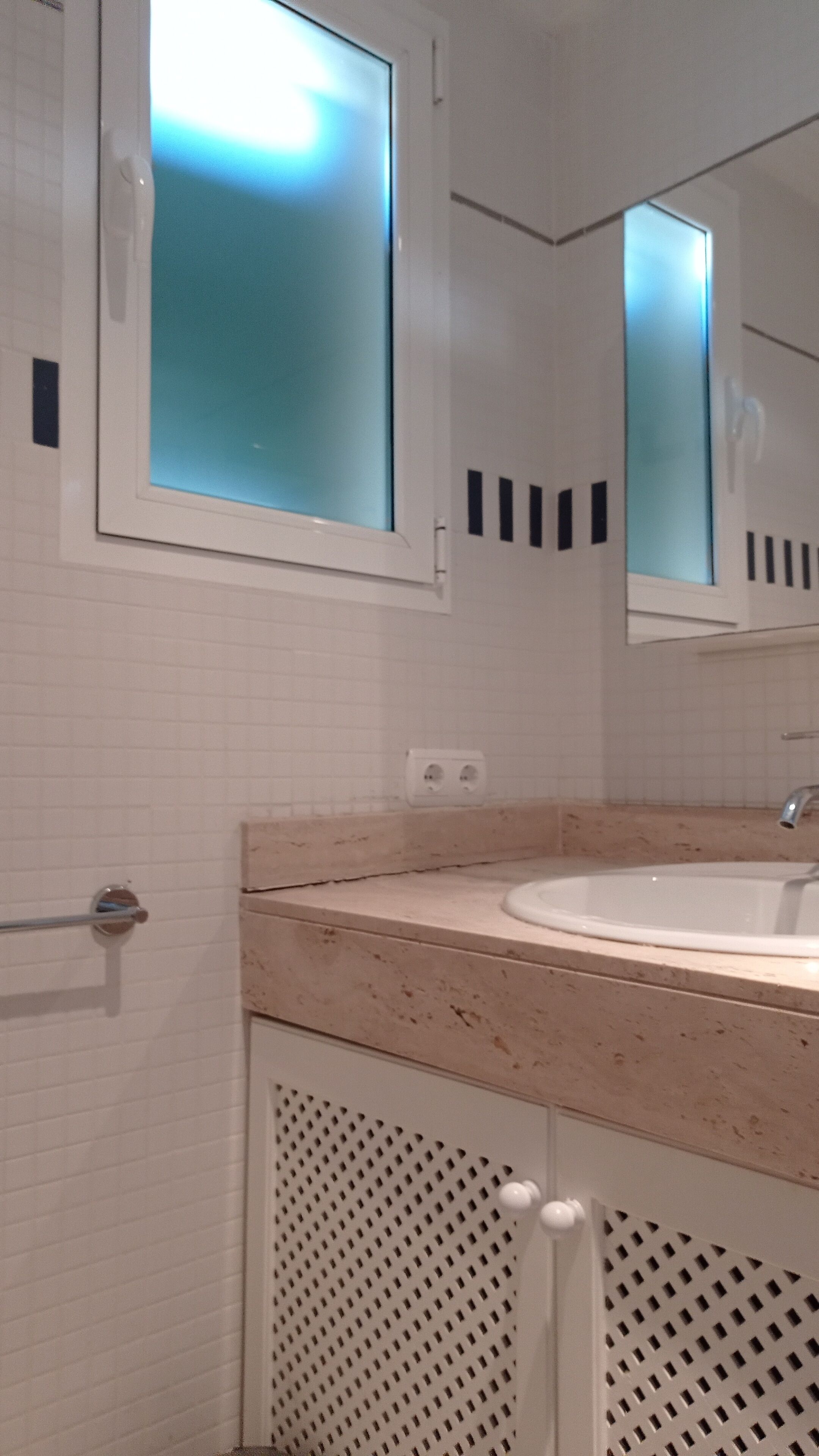 Ein Badezimmer mit einem weißen Waschbecken, einem Spiegel und einem Handtuchhalter.