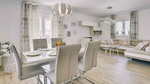 Ein modernes Wohnzimmer mit Sofa, Esstisch, Stühlen und Küchenzeile.