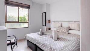 Une chambre à coucher avec un lit, une chaise, une fenêtre avec des rideaux et une table de chevet.