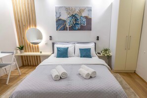 Un dormitorio moderno con cama, mesitas de noche, un escritorio y un armario.
