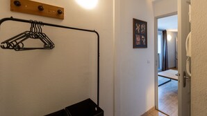 Un corridoio con un attaccapanni, un pannello in legno e una porta che dà su un'altra stanza.