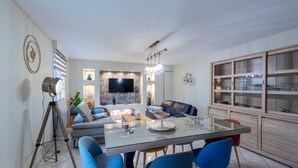 Ein modernes Wohnzimmer mit einem Glastisch, blauen Stühlen, einem Ledersofa, einem an der Wand montierten Fernseher und einer Fahrraddekoration.