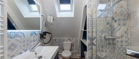 A compact bathroom with a skylight, a shower with a glass door, and a toilet.