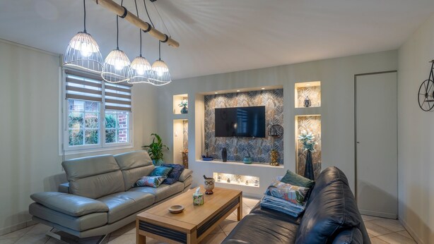 Ein modernes Wohnzimmer mit Sofa, Couchtisch und Pendelleuchten.