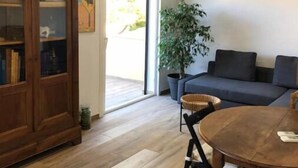 A living room with a wooden cabinet, a dark sofa, a round wooden table, and a potted plant. - Superbe T2 Neuf à Carry le Rouet Avec Toit Terrasse Privatif (Carry-le-Rouet)
