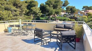 A terrace with outdoor furniture, a table, and chairs. - Superbe T2 Neuf à Carry le Rouet Avec Toit Terrasse Privatif (Carry-le-Rouet)