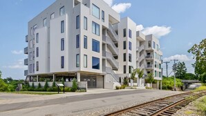 Un immeuble moderne à plusieurs étages, doté d’un toit plat, de grandes fenêtres et d’un espace de stationnement couvert.