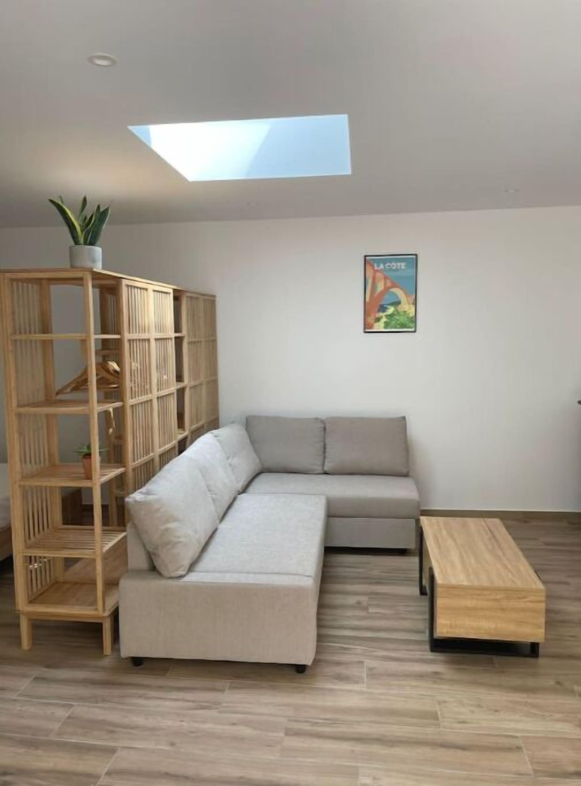 A modern living room with a sectional sofa, a wooden shelving unit, and a small wooden table.