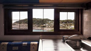 A kitchen with a large window overlooking a coastal landscape.