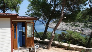 A small wooden building with a door and steps leading to a white chair outside.