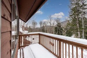 A wooden deck with snow on the railing, overlooking a snowy landscape with trees and mountains. - South Ridge G-01 - Sunday River Condo (Newry)