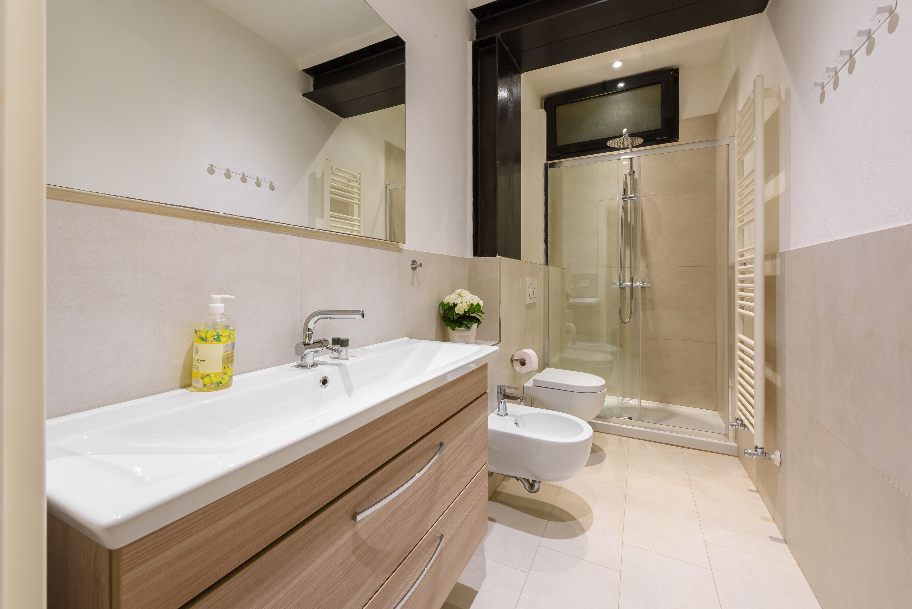 Un baño moderno con un lavamanos grande, tocador, bidé y cabina de ducha con paredes de vidrio.
