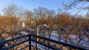 A metal railing overlooking a snow-covered landscape with bare trees and a street lamp.