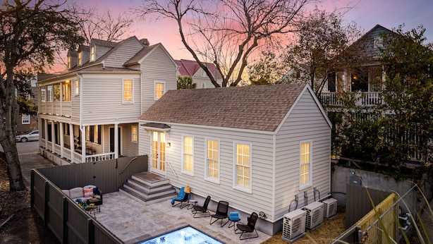 A two-story house with a backyard pool, outdoor seating, and a covered patio area.