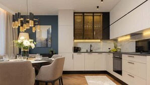 A modern kitchen with white cabinets, a black countertop, and a dining area with a table and chairs.