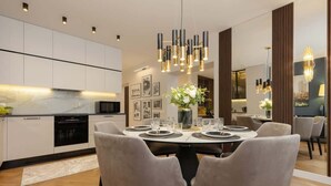 A modern dining area with a round table set for six, surrounded by grey upholstered chairs.