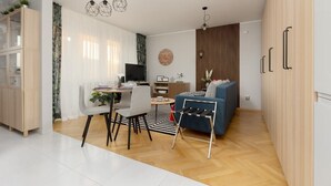 A modern living room with a dining area, a blue sofa, and a TV. - Modern Apartment in Zoliborz | Balcony and Workspace (Warszawa)