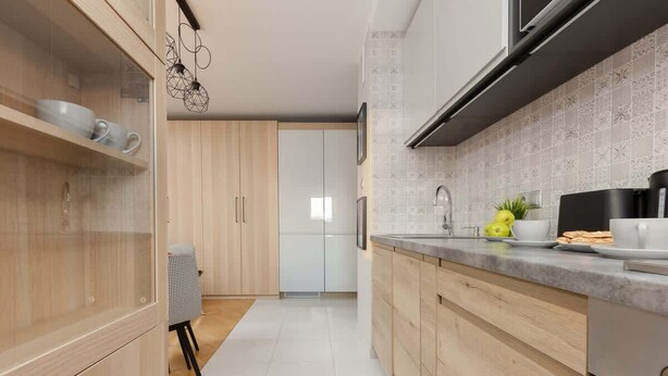 A modern kitchen with wooden cabinets, a countertop with kitchen appliances, and a tiled backsplash. - Modern Apartment in Zoliborz | Balcony and Workspace (Warszawa)
