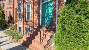 A brick building with a green door, a staircase, and a small tree in front. - Extremely clean and Affordable.  (Boston)