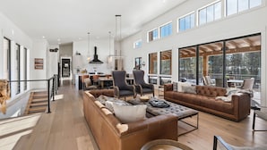 A spacious living area with a large sofa, a coffee table, and a dining area with chairs and a table.
