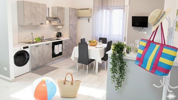Una cocina moderna con armarios grises, una lavadora y un comedor con una mesa preparada para dos.