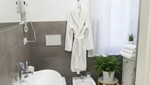 Un baño moderno con bañera, inodoro, bidé y una pequeña planta en maceta.