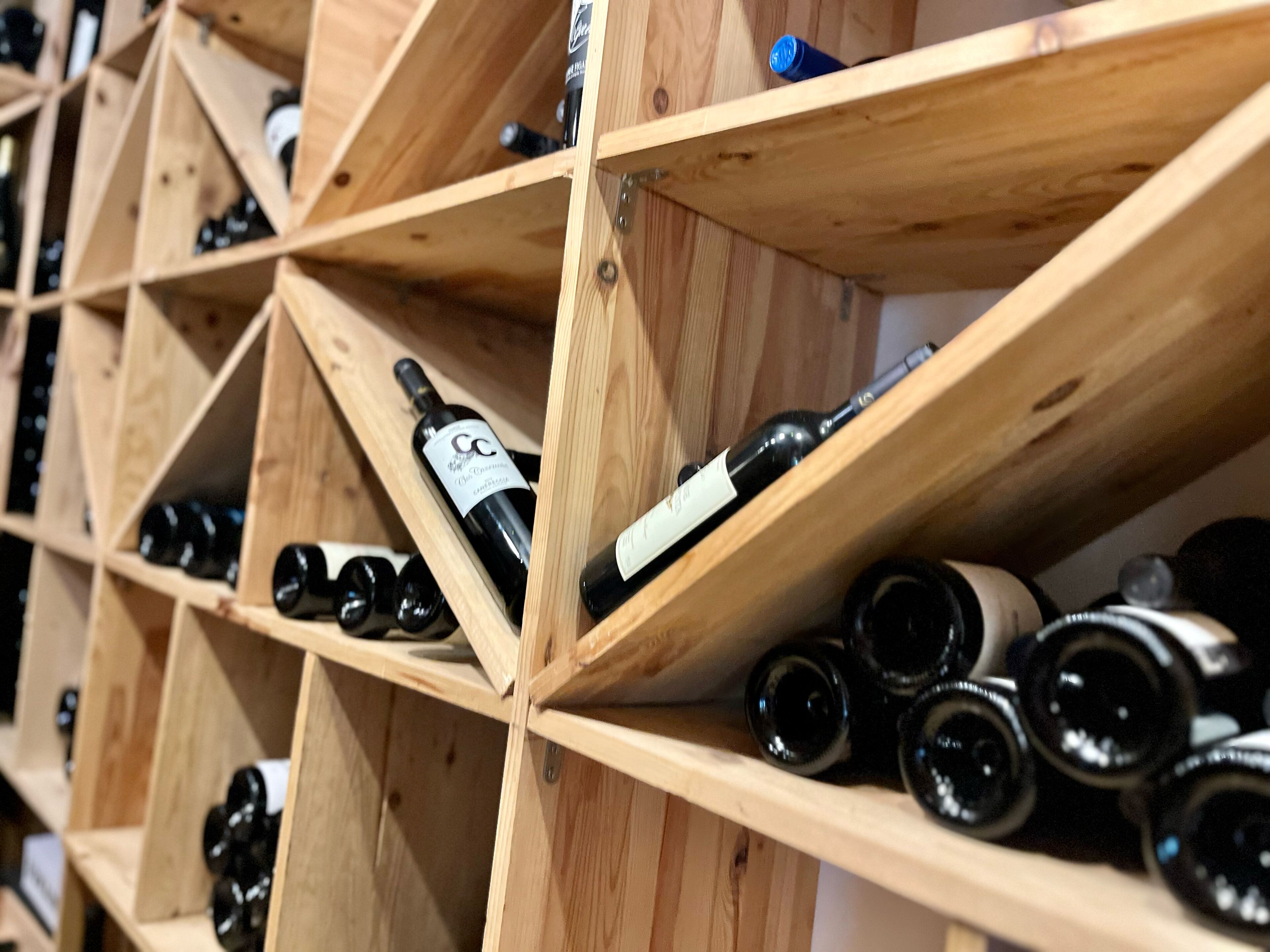 Una botellera de madera con varias estantes que sostienen botellas de vino.