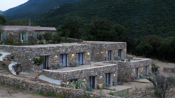 Una casa de piedra con varios balcones y vistas a una montaña boscosa.