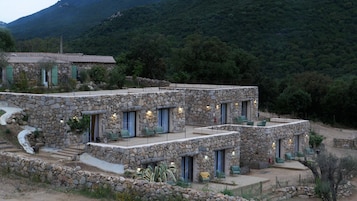 Una casa de piedra con varios balcones y vistas a una montaña boscosa.