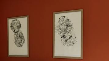 Une chambre à coucher avec un lit, des oreillers blancs et deux œuvres d’art encadrées accrochées au mur.