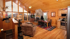 L’intérieur d’un chalet en bois comprend un coin repas, une cuisine et une cheminée.