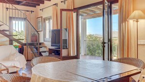 A spacious living area with a round table, wicker furniture, a television, and a balcony with a view. - S'Albufereta by Rentallorca (Alcúdia)