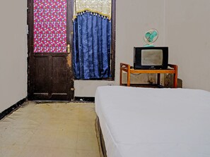 Simple room with a single bed, small table, and vintage TV.