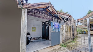 A building entrance with a metal gate, a motorcycle parked inside, and a sign indicating a parking area. - OYO Life 92709 Kost Teras Cikapundung Syariah (Bandung)