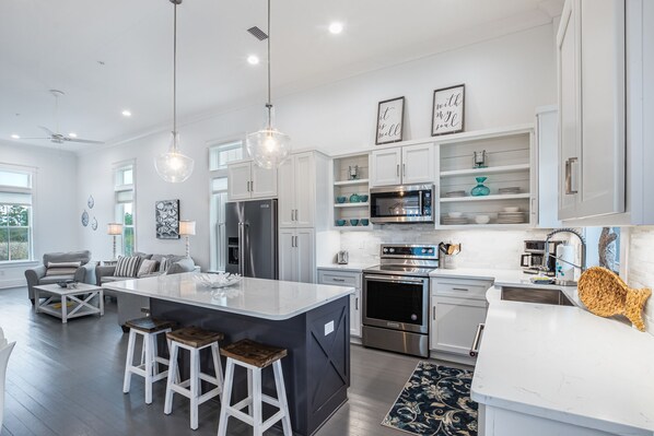 A modern kitchen with a central island, stainless steel appliances, and white cabinetry.